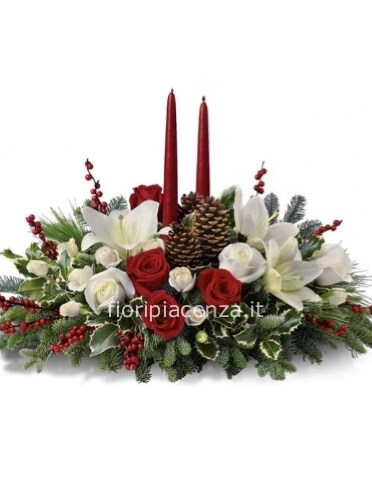 Composizione natalizia con fiori rossi e bianchi, candele e abete con altri decori..
